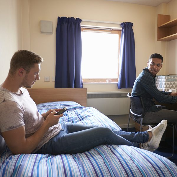 Male Students Working In Bedroom Of Campus Accommodation